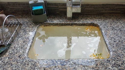 Backed-up kitchen sink during a drain emergency in Southeast Michigan, showing water not draining from a clogged line.