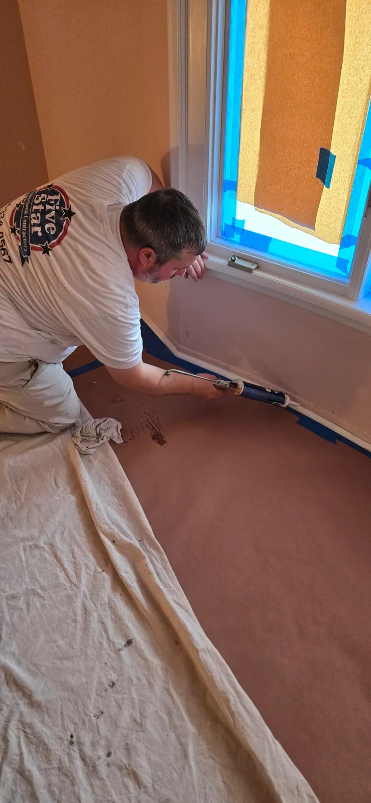 Painter caulking interior trim gaps before painting in Canton MI home preparation phase